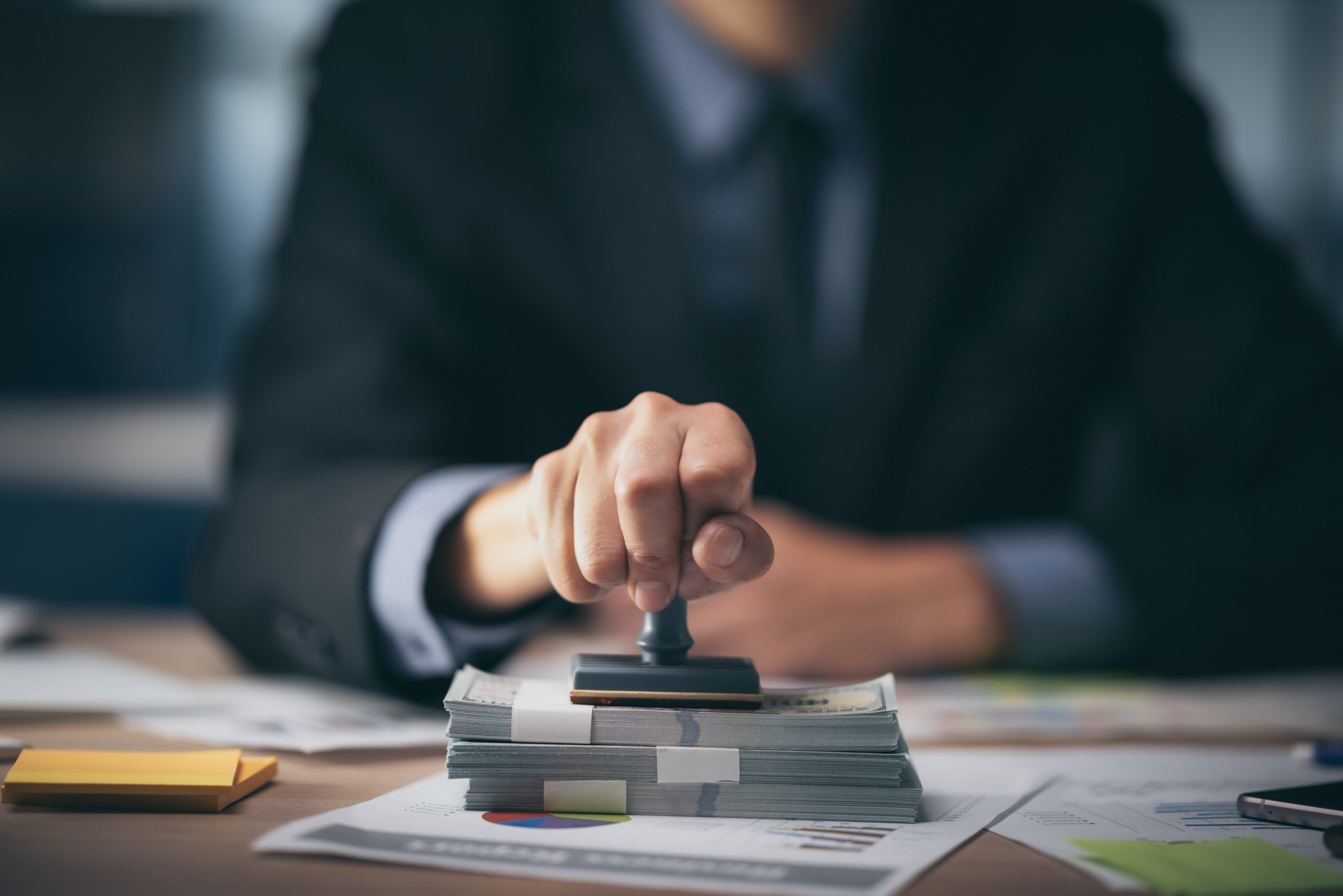 Business person stamping a pile of bills