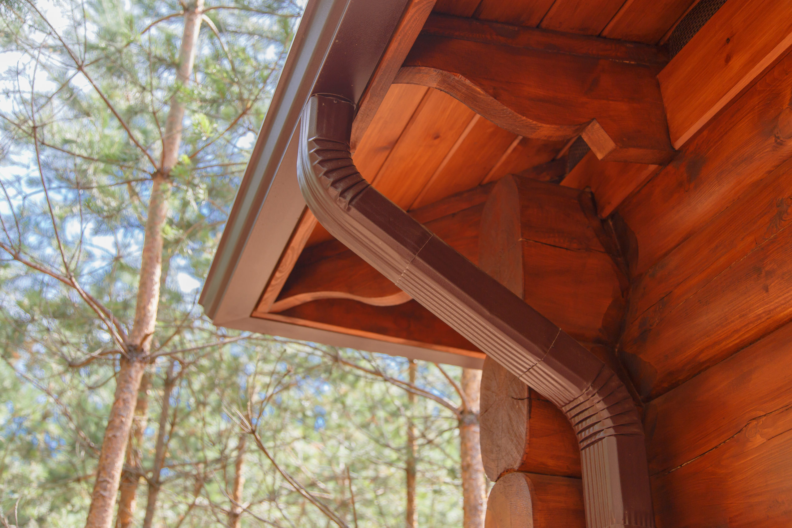 Brown roof gutter on corner of log cabin