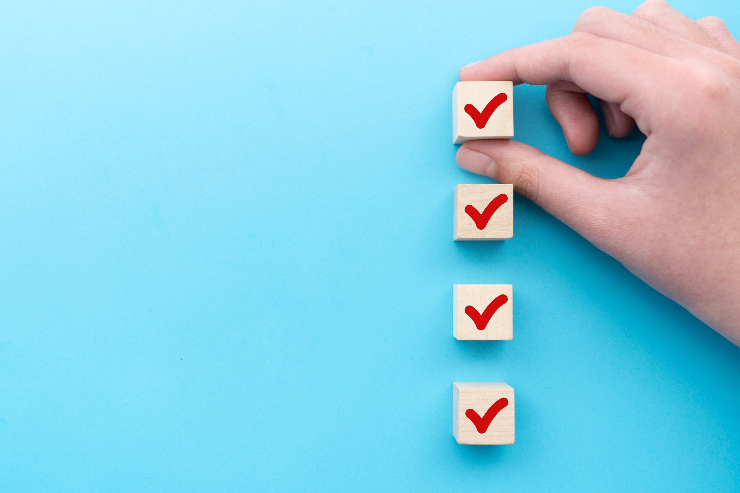 Hand placing square wood boxes with checkmarks against blue background