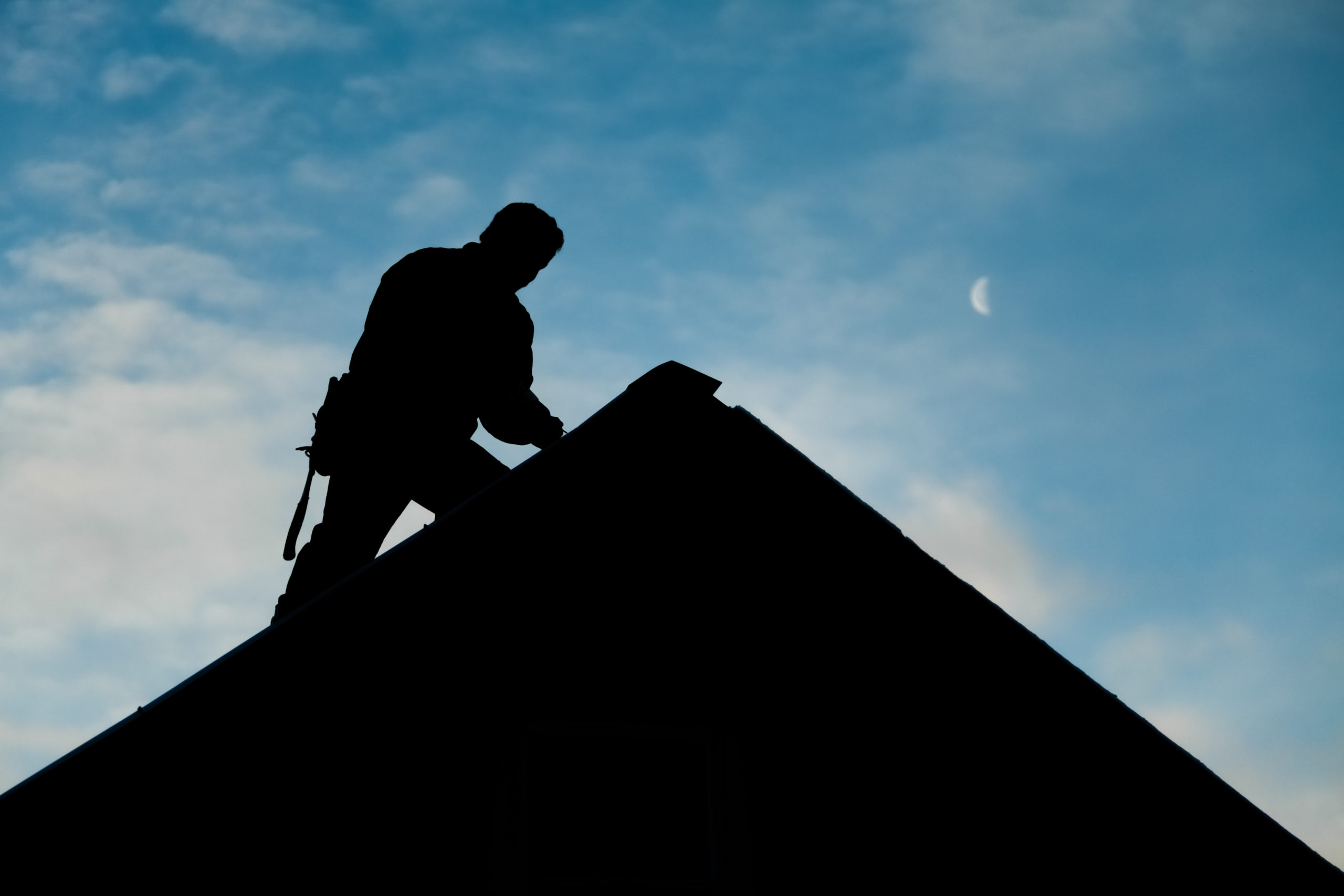 Silhouette of contractor working on roof