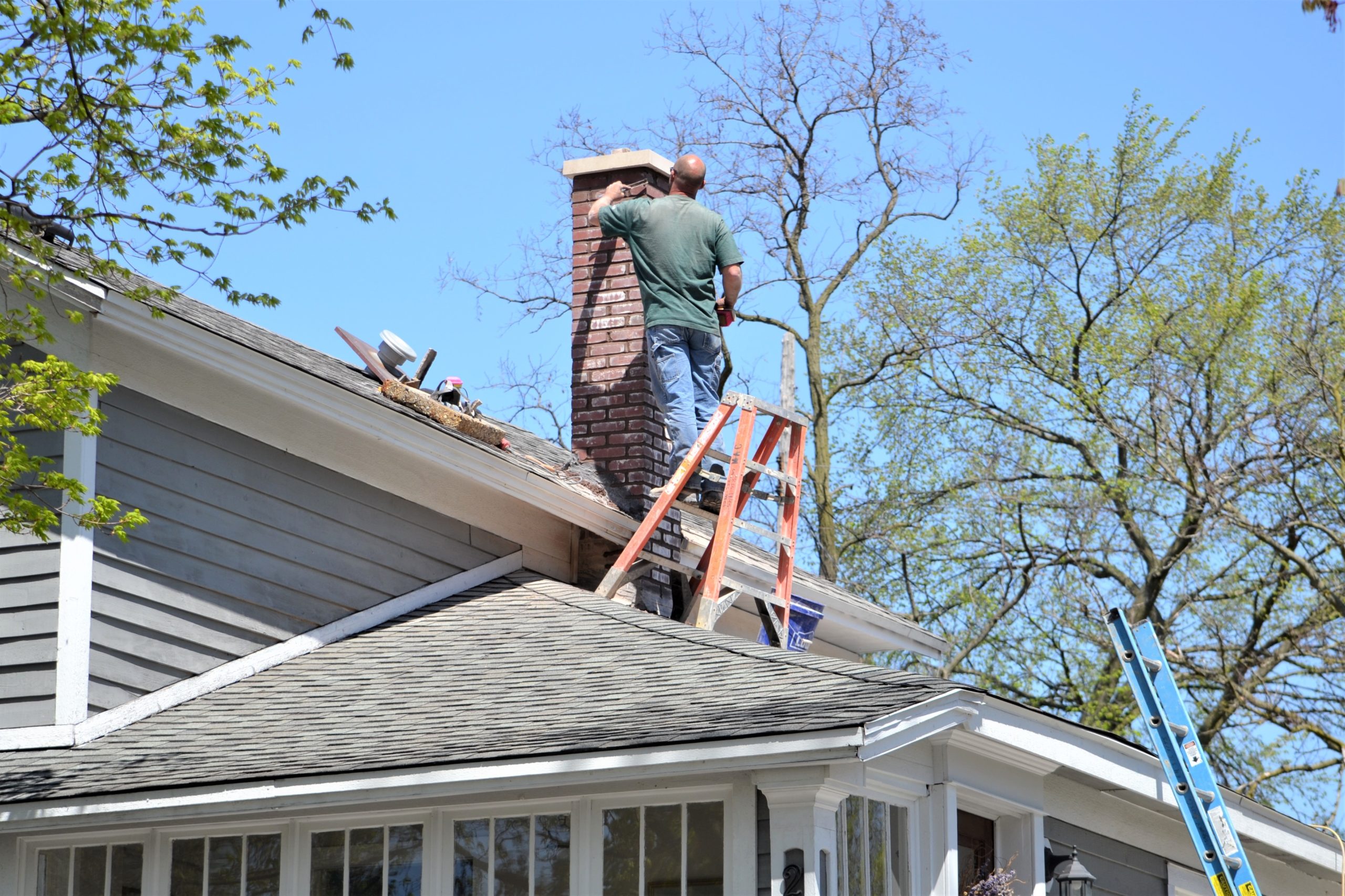 Man doing work on chimney with a ladder